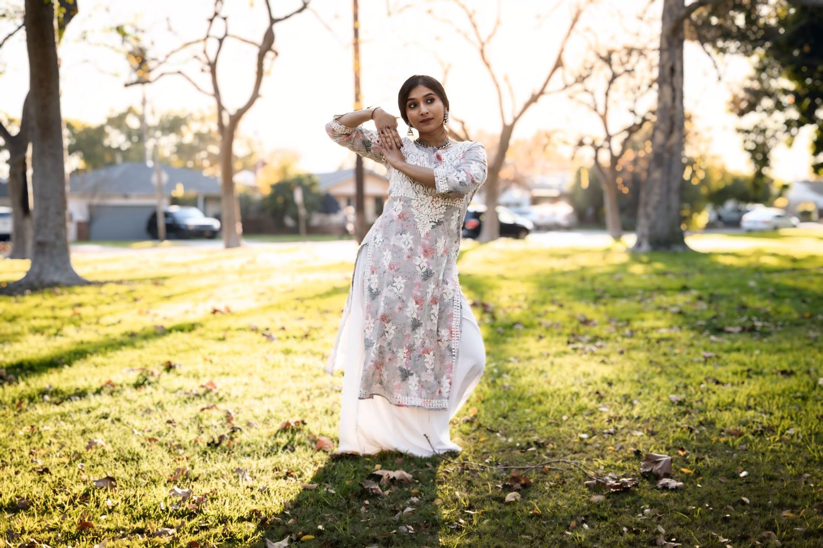 Yaman in a floral kurta posing on grass at golden hour, smiling over one shoulder.