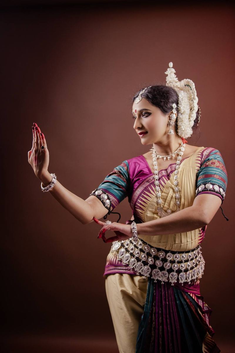 Studio profile in cream and magenta silk, one palm raised flat before the face in a held gesture.