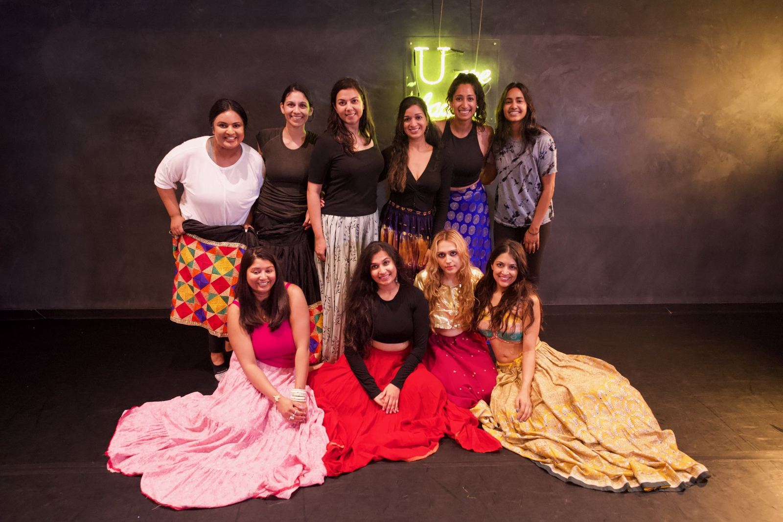 Workshop group in full costume seated and standing on the studio floor before a showcase.