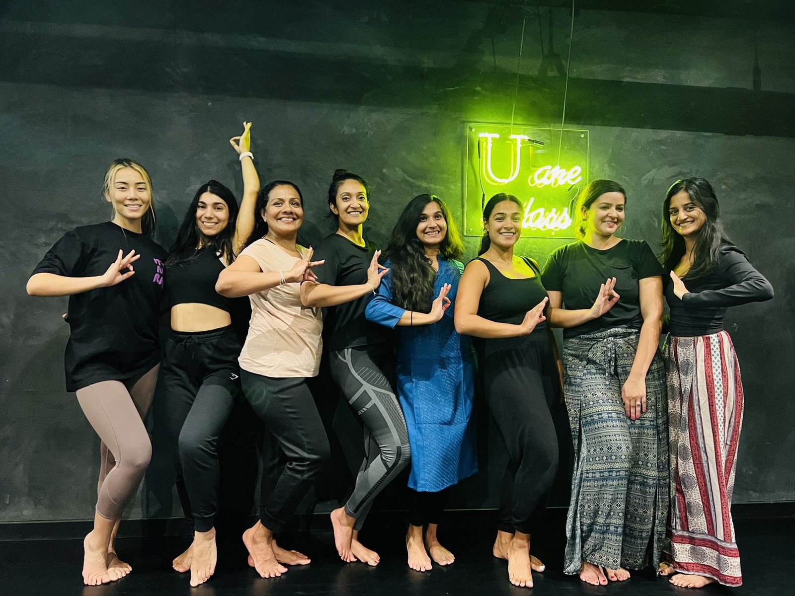 Students lined up in the studio holding a hand mudra together at the end of an Odissi class.