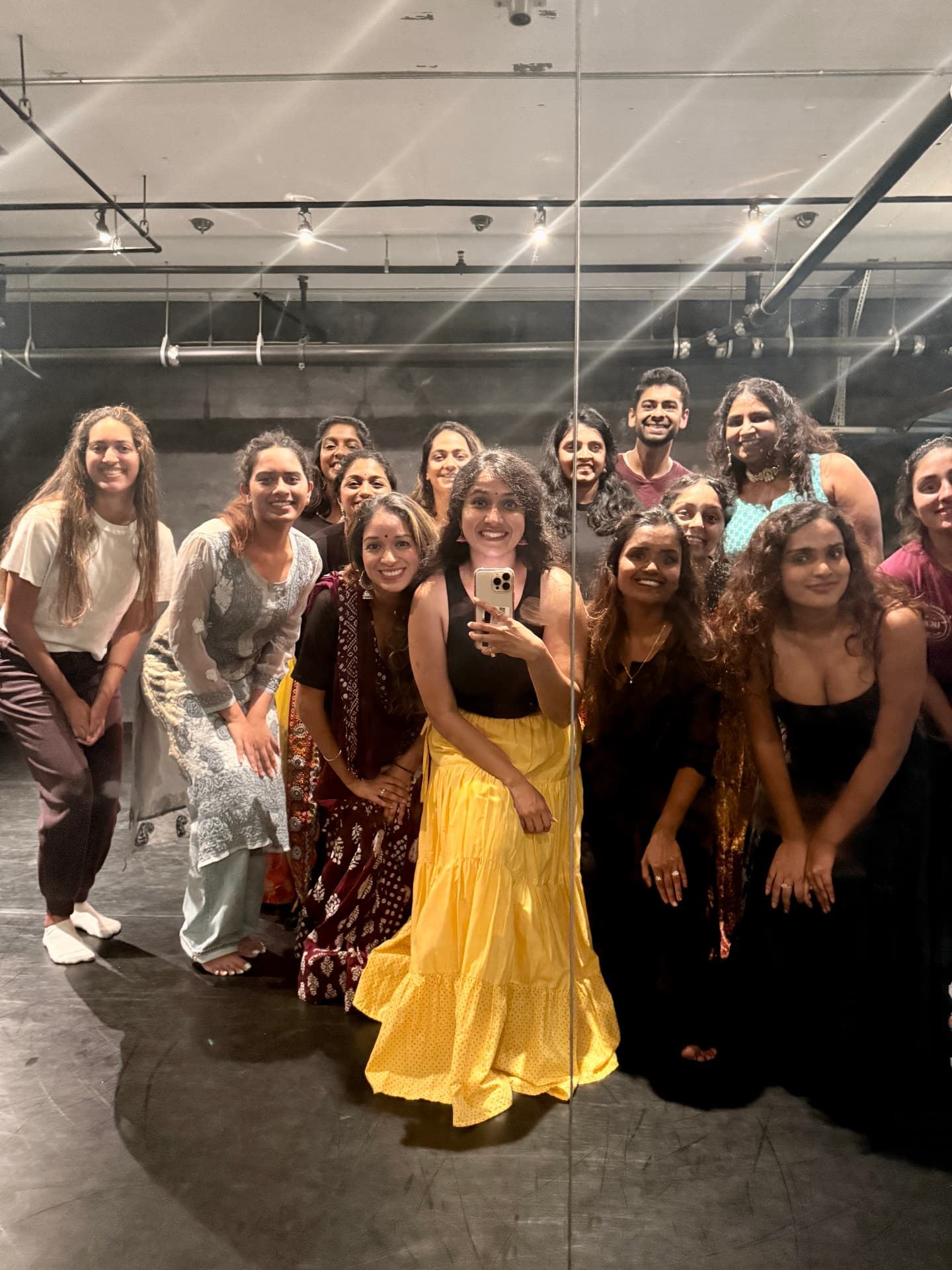 Yaman with a full class of adult students in the studio mirror after a session, everyone smiling.