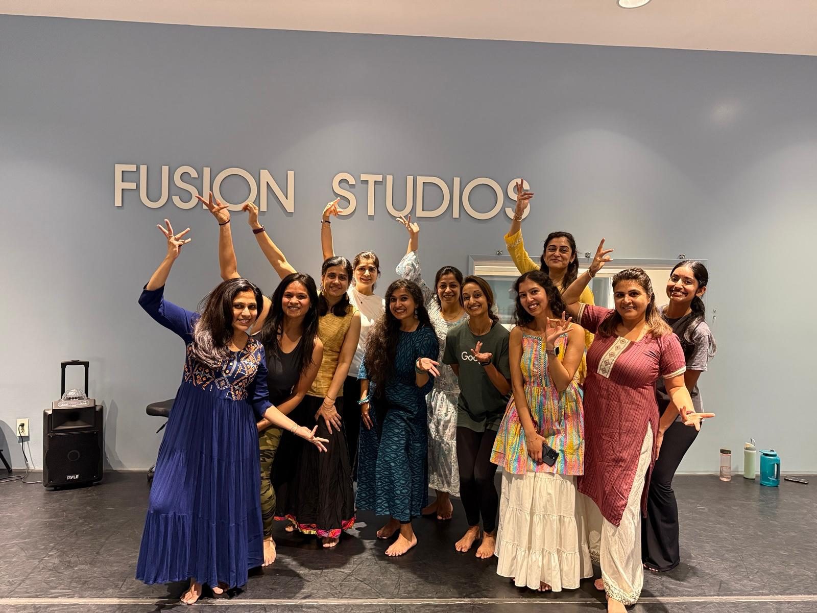 Yaman with a workshop group posing in mudras under the Fusion Studios sign after class.
